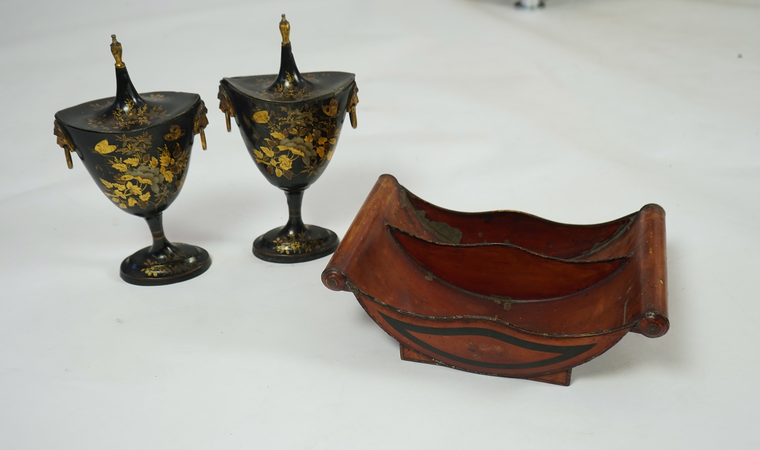 A pair of early 19th century Dutch japanned pewter chest urns and covers, and a tole ware cheese coaster